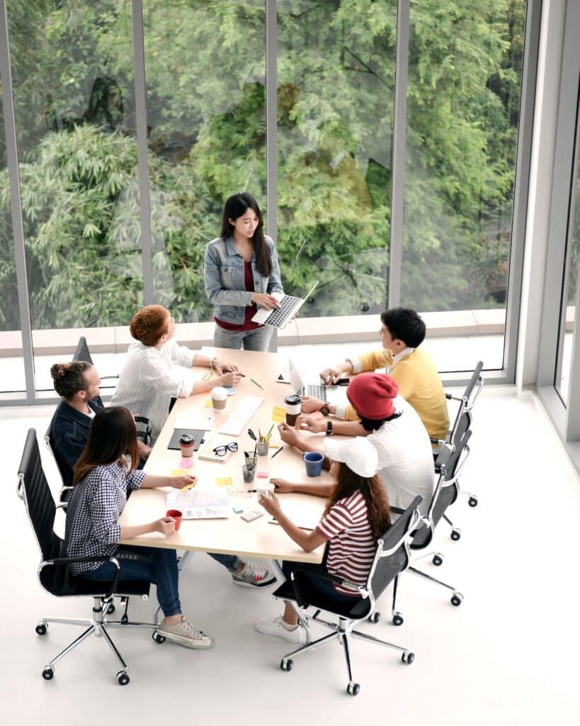 Group of business persons sitting around a desk listening to and discussing about a presentation by a colleague at the office